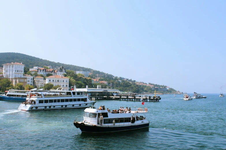 several ferry boats pass each other in front of a shoreline with houses on it