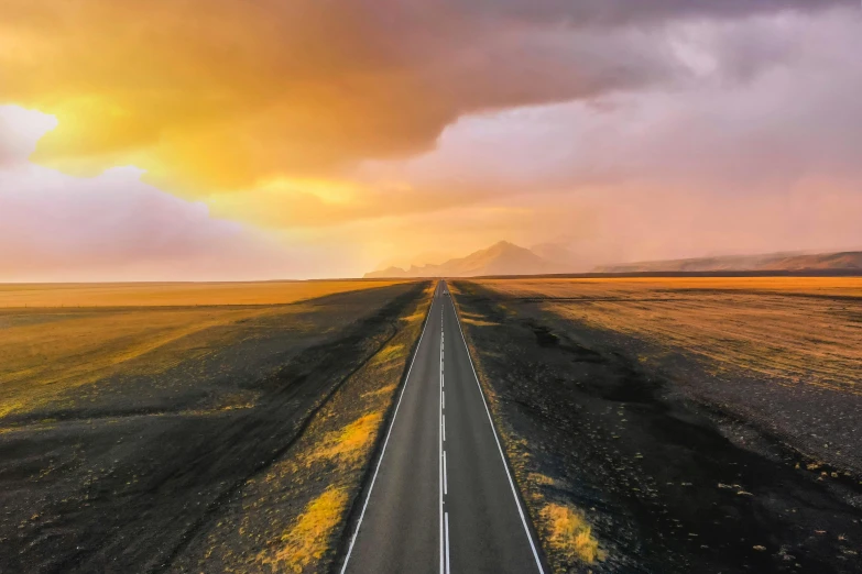 a lone road with some cars driving down it near some mountains