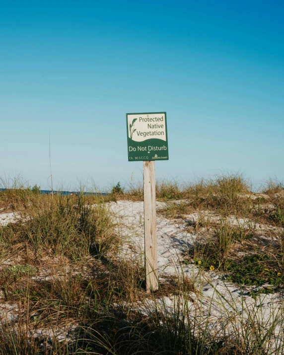 a wooden sign in some brown grass and dirt