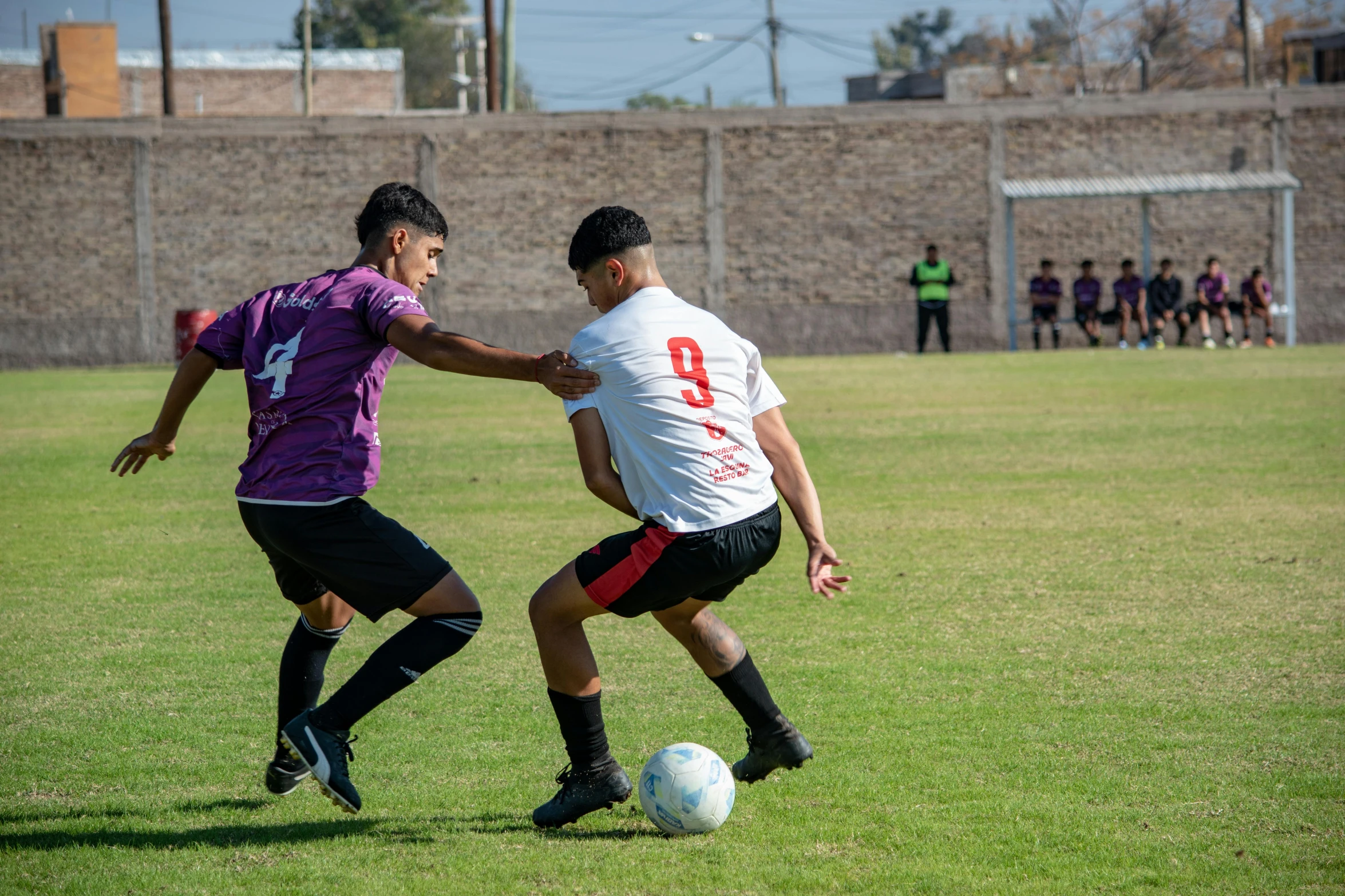 two young men playing soccer against each other on a field