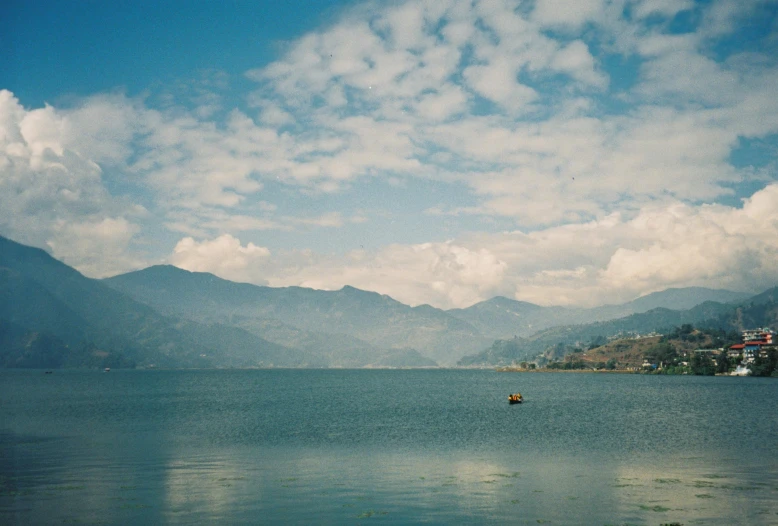 boat on water surrounded by mountains under cloudy sky