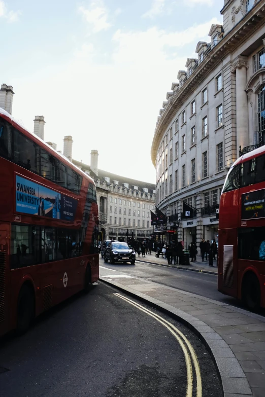 two double decker buses on the road in london