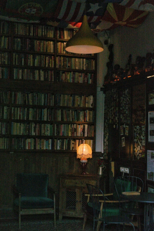 a dimly lit bookcase with a lamp on it