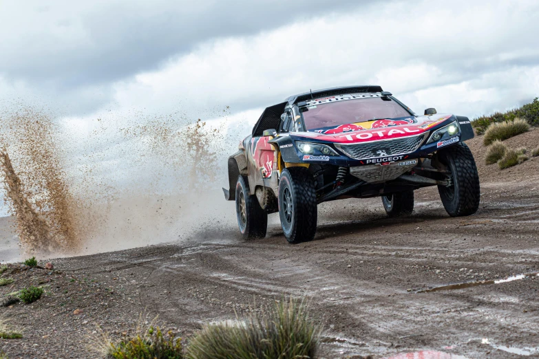 a car is going through a field with mud blowing out of the back