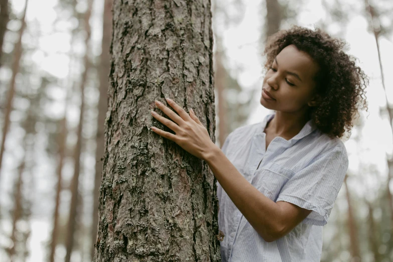 a woman hugging a tree with both hands