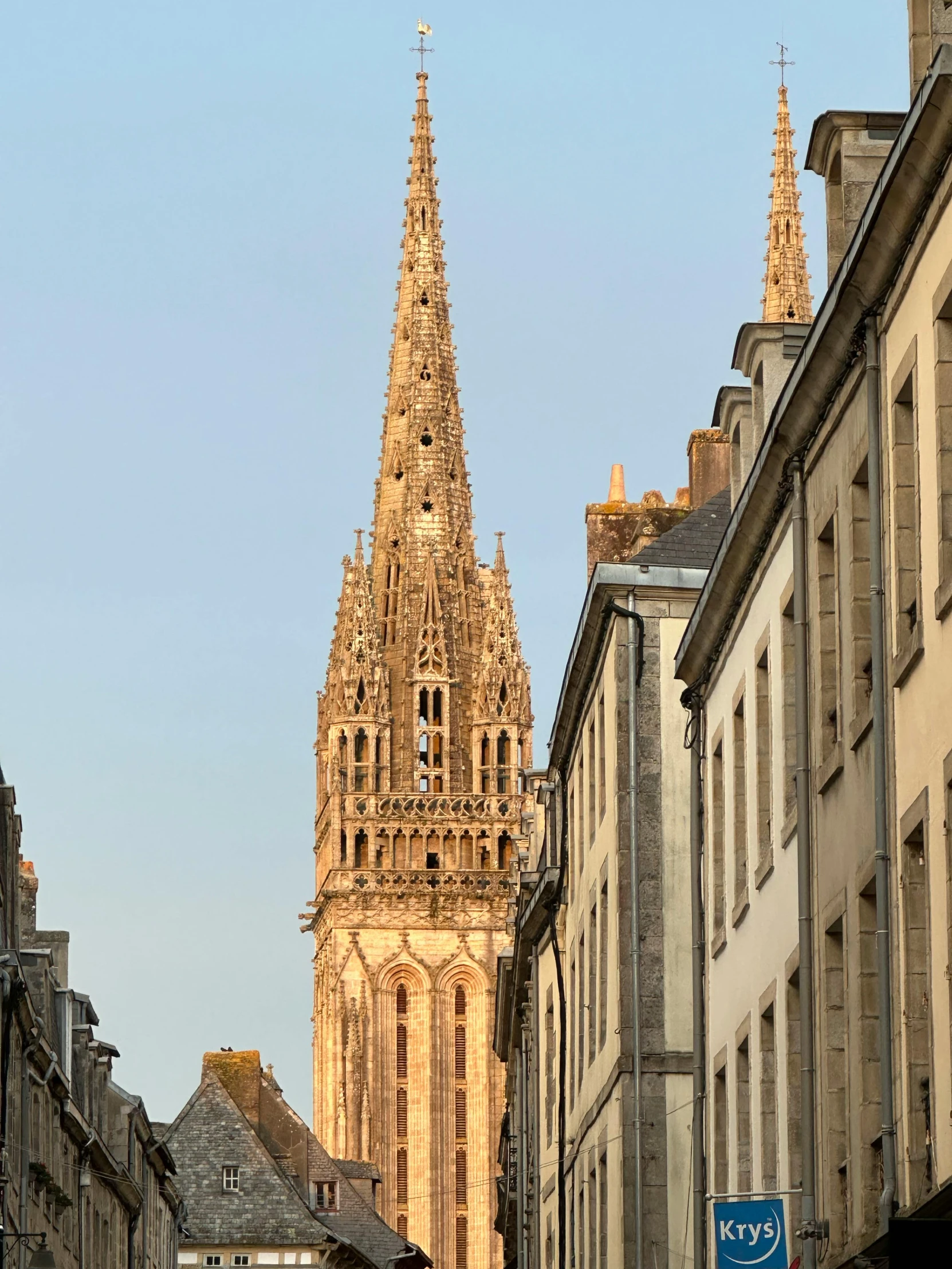 cathedral spire with clock in city area on sunny day