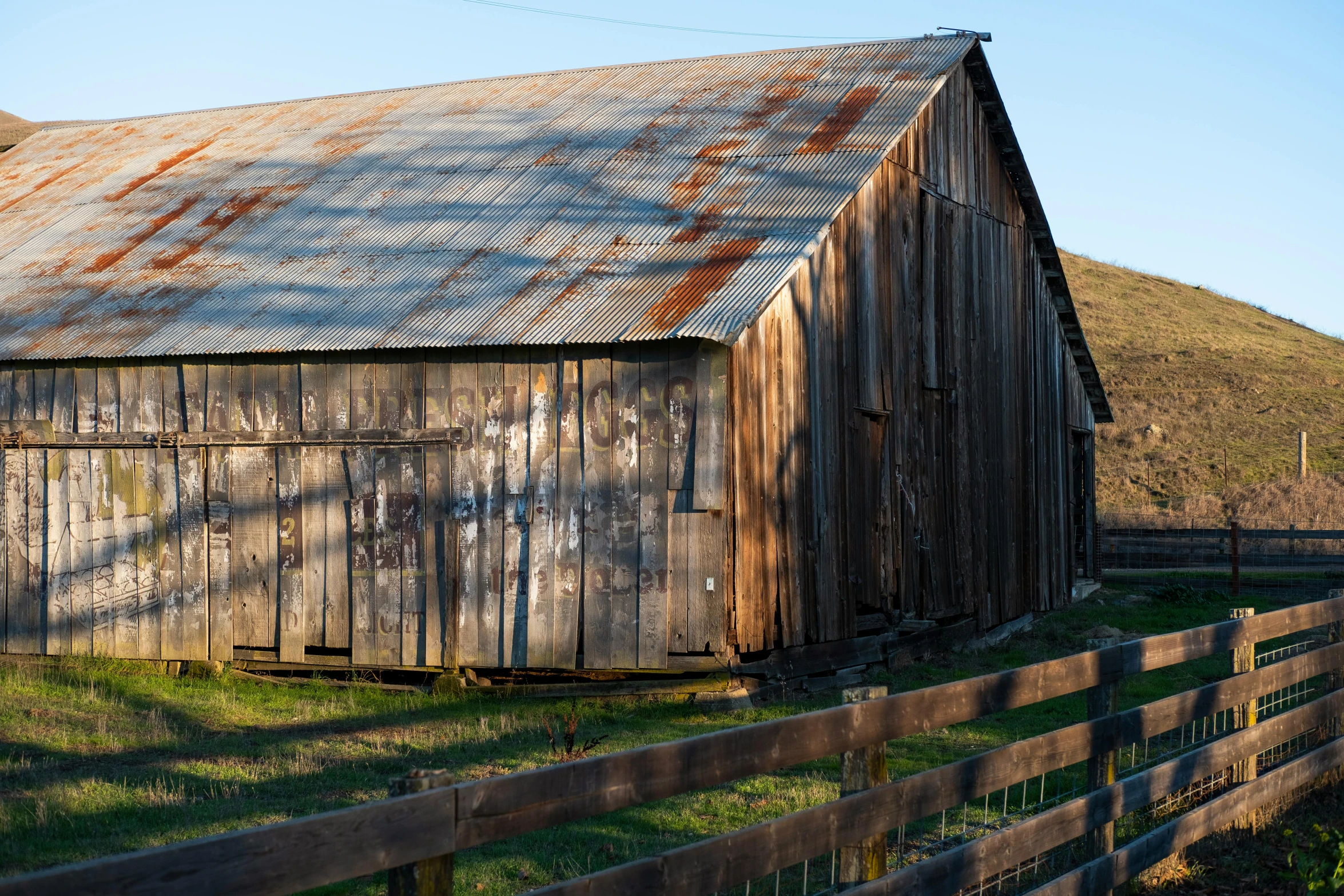 a wooden shed stands on the side of a fence