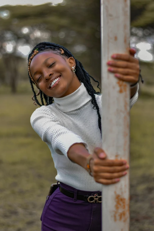 young african woman smiling on wooden pole in park