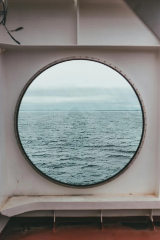 the ocean seen through a porthole window on a boat