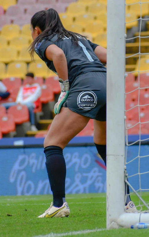 woman in black jersey and knee ces leaning up against a soccer goal