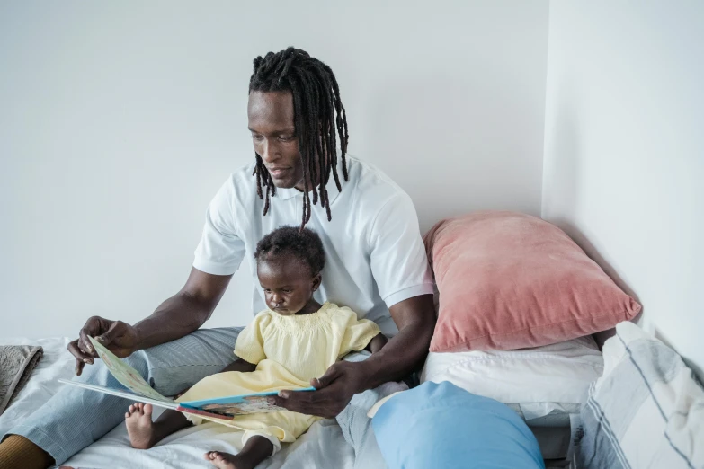 a man reading a book to a little girl in bed