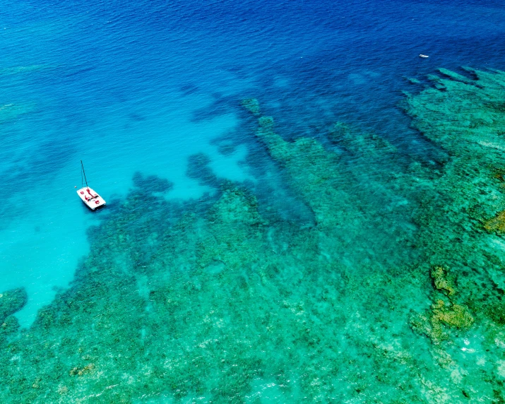 a small boat sitting in clear blue water next to the ocean