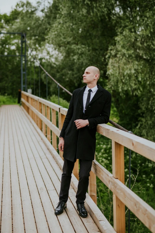 man in business attire standing on a deck with his hand on his hips