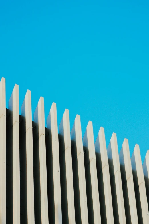 a bird flies over a concrete fence on a sunny day