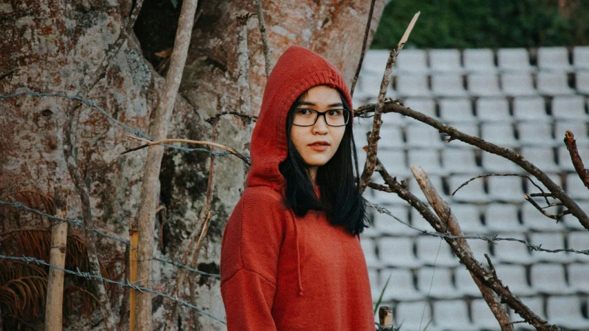 a person wearing glasses is standing behind the trees