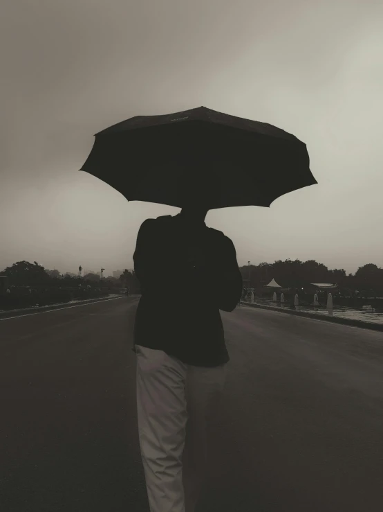 a person walking down the road holding an umbrella over their head