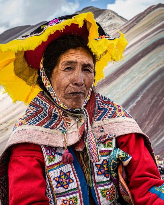 an old man with colorful clothing poses in front of a mountain