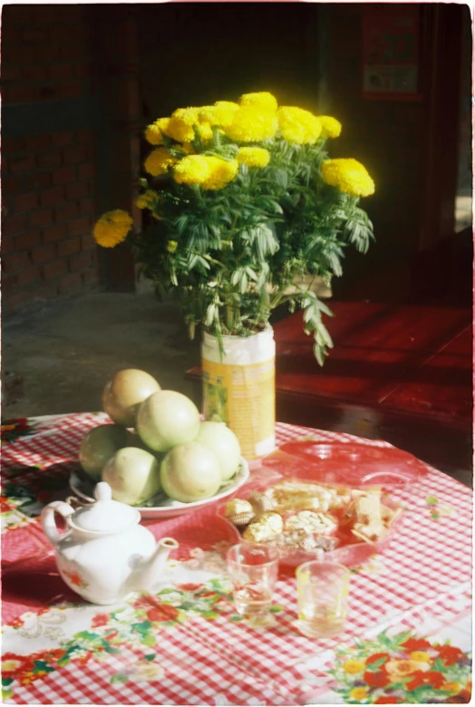 a table topped with flowers and fruits near an umbrella