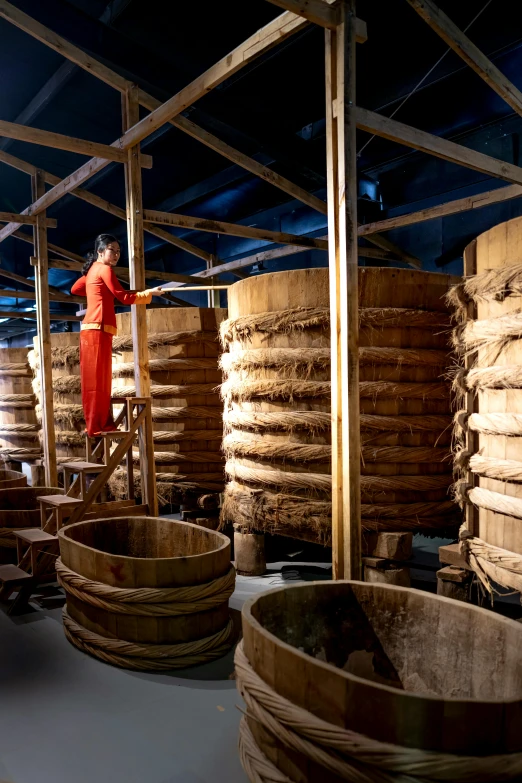 man on step next to stacked wooden barrels