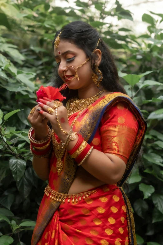 a woman dressed in a sari smelling a rose
