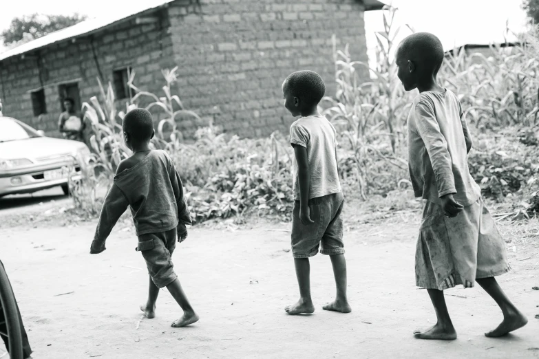 a group of young children walking around a dirt road