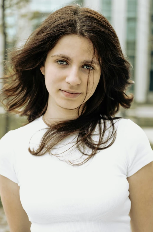 a woman standing in front of a building wearing a white shirt