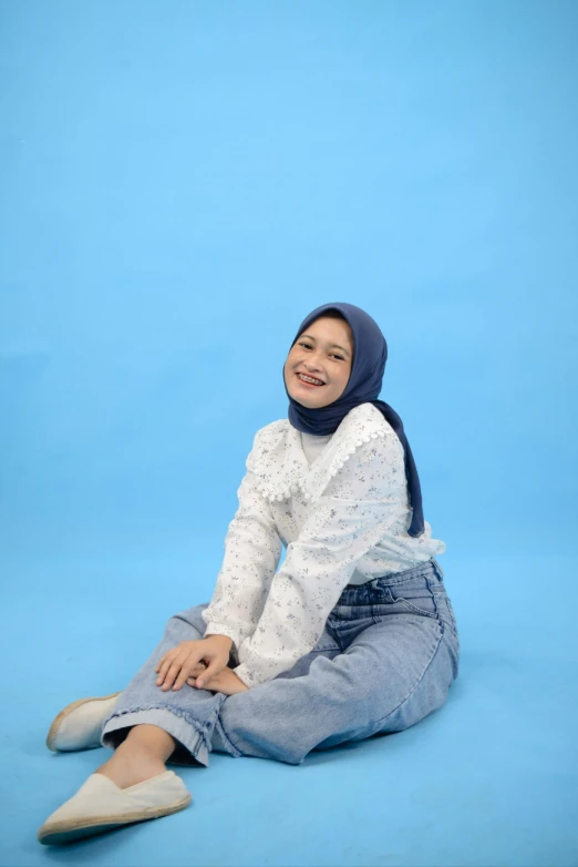 a child in jeans and hoodie sitting on the floor