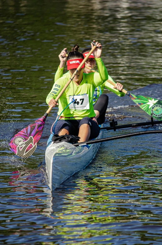 three people wearing neon vests rowing in the water