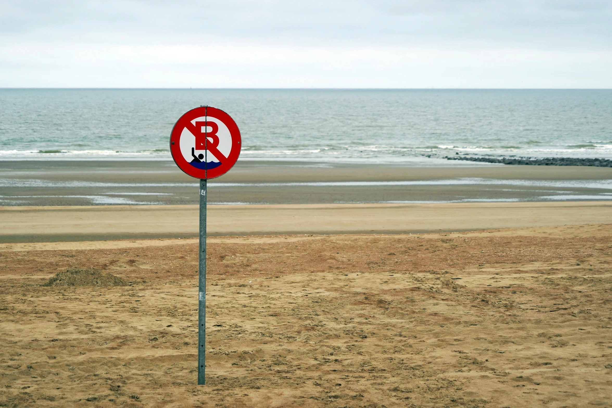 a sign on a post on the beach