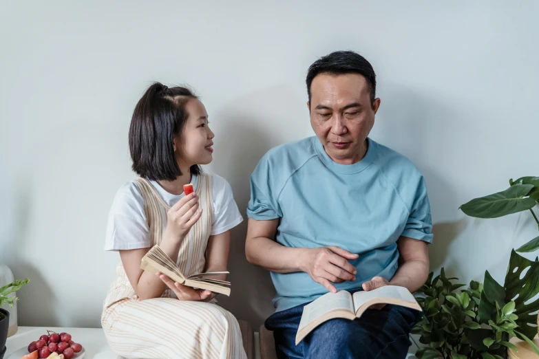 the man and girl are sitting down together reading the book