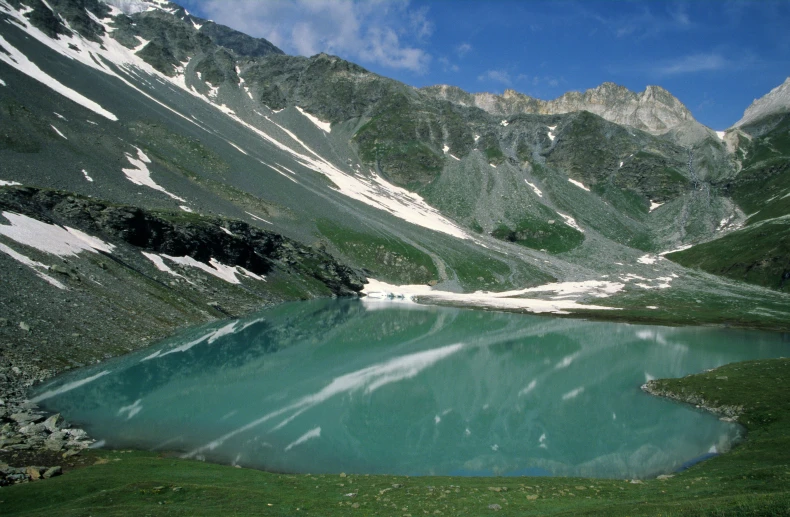 a large mountain is covered in snow and green grass
