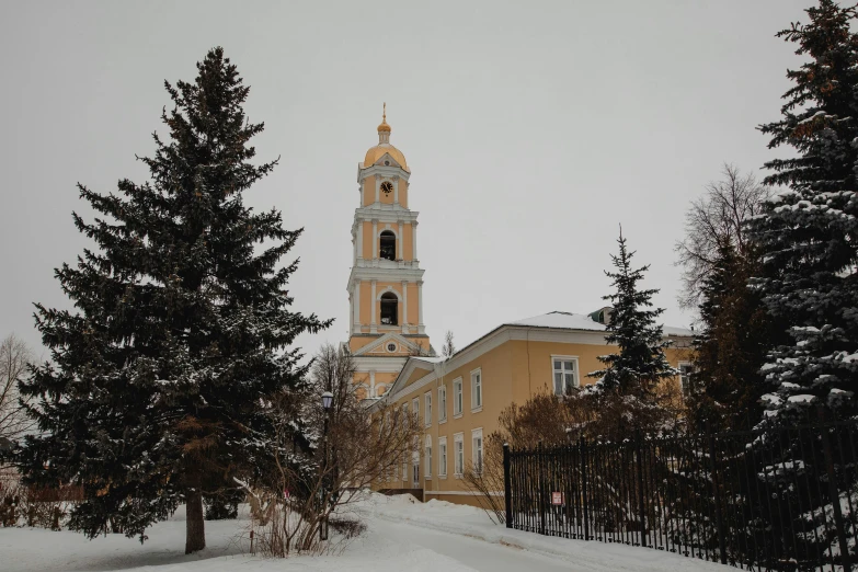 a church that has a clock tower with snow around