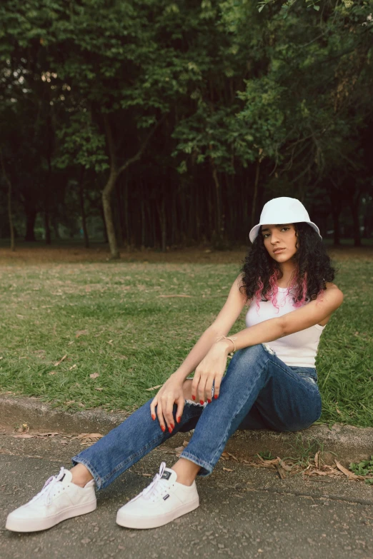 a young lady is posing while sitting on the curb