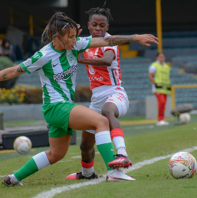 two women in uniforms playing soccer on the field