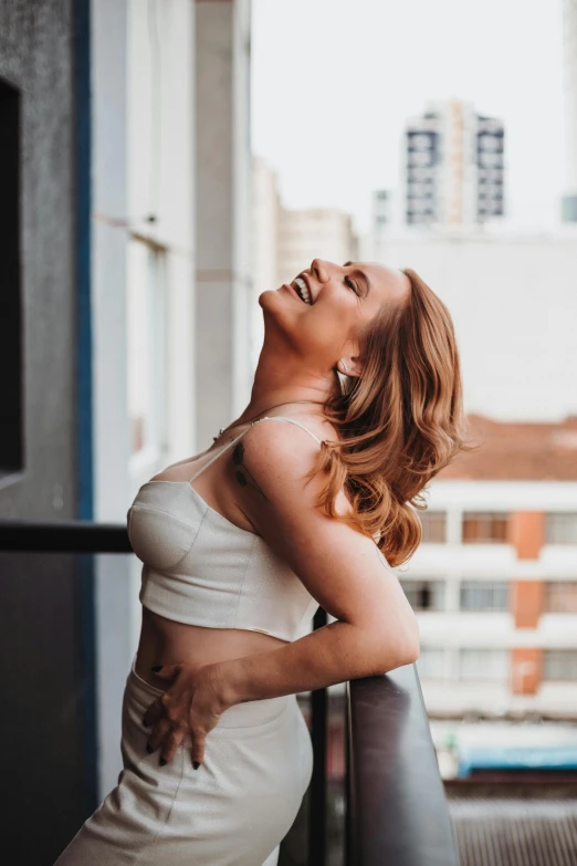 the woman in white dress is posing by the railing