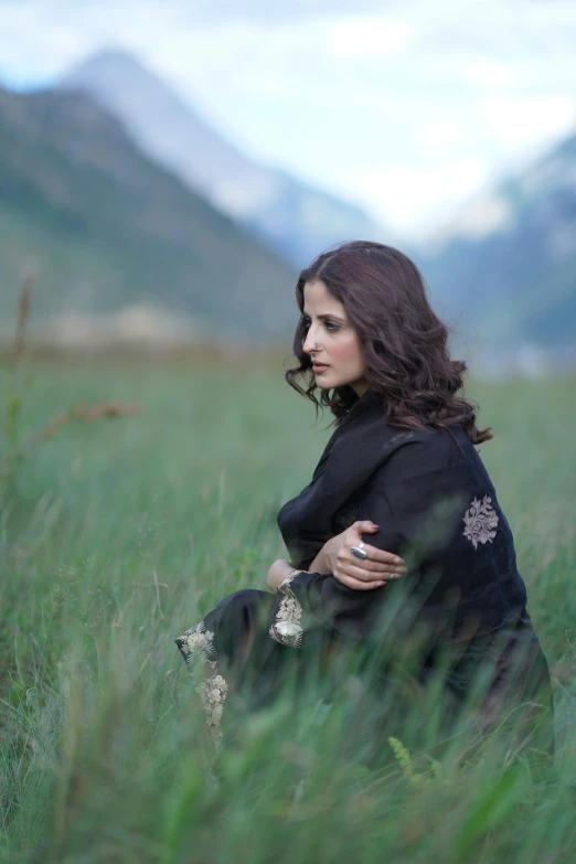 a woman is sitting in a grassy field