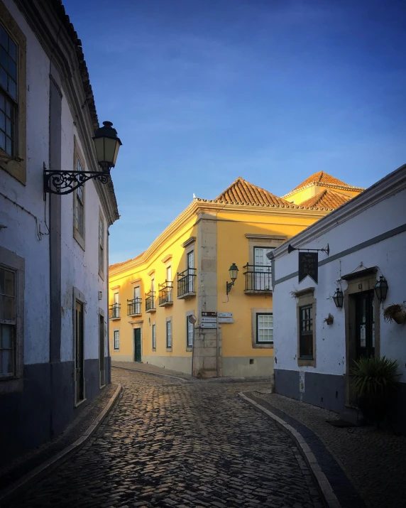 a cobblestone street in front of some white buildings at night