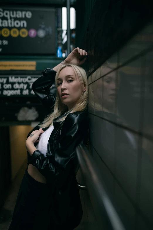 a woman leaning up against the wall in a subway station