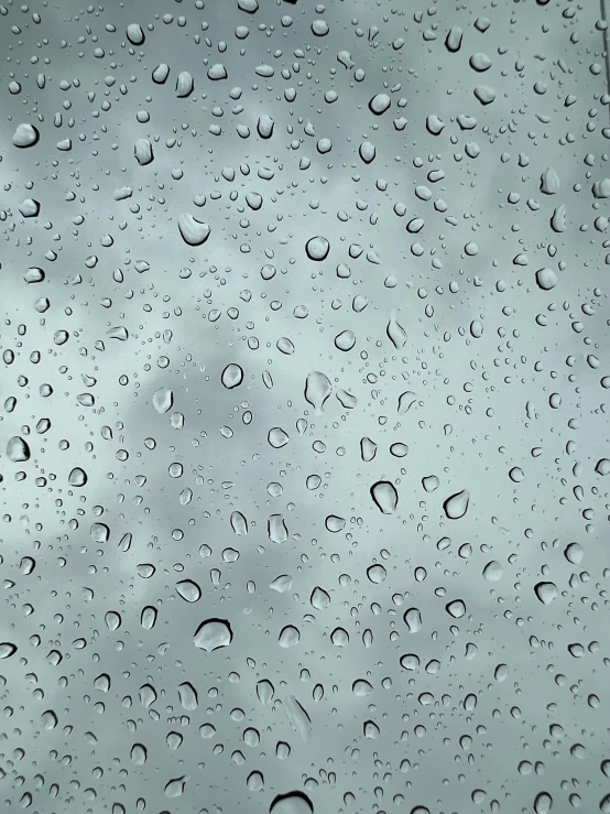 rain drops on a glass window with a sky in the background