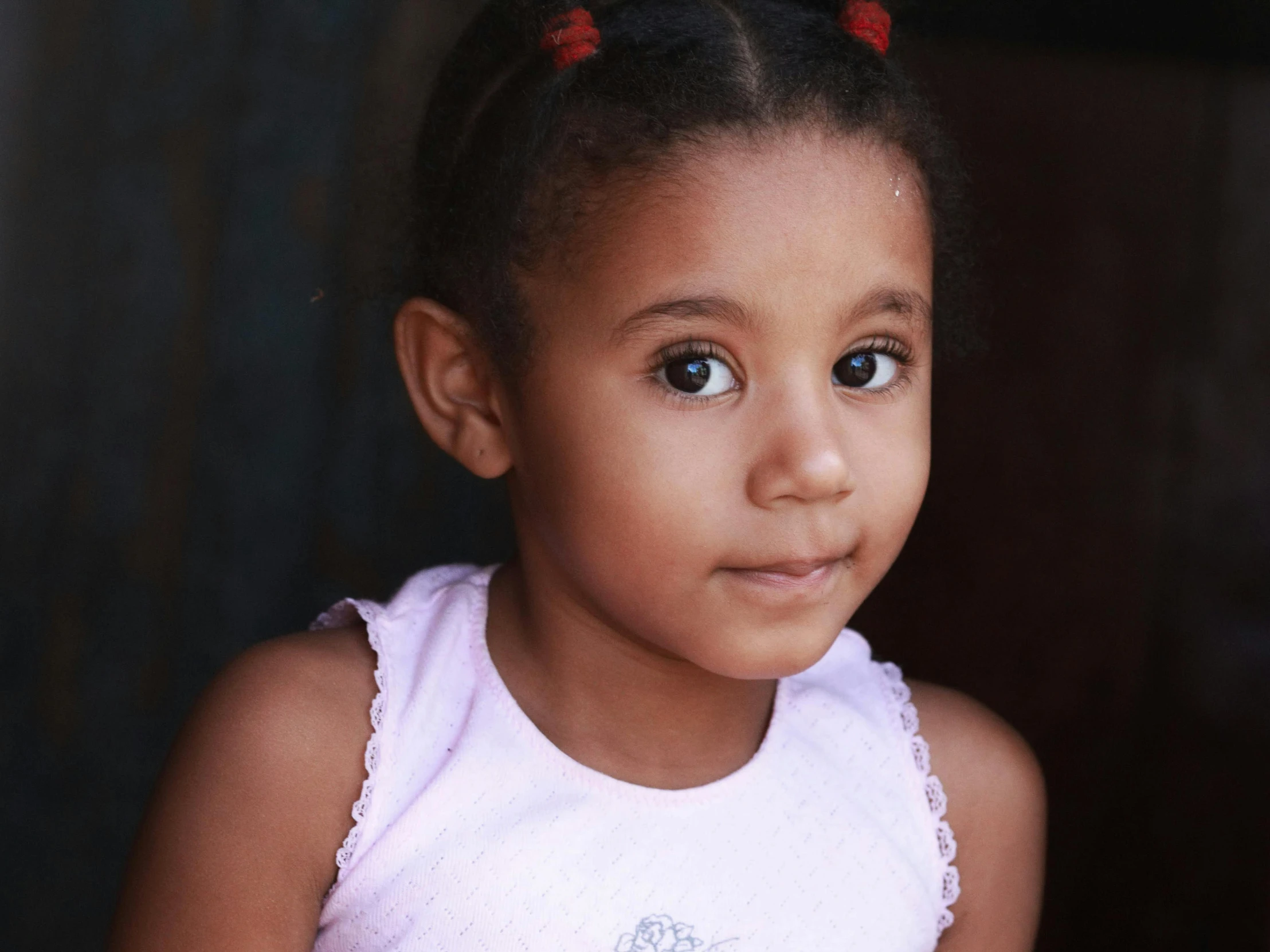 a little girl with two pony tail sitting down and smiling