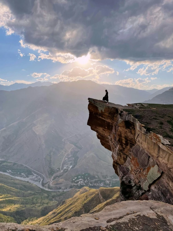 a man sitting on a ledge that overlooks a river valley