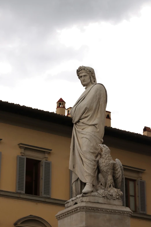 a statue with a dog stands next to a building