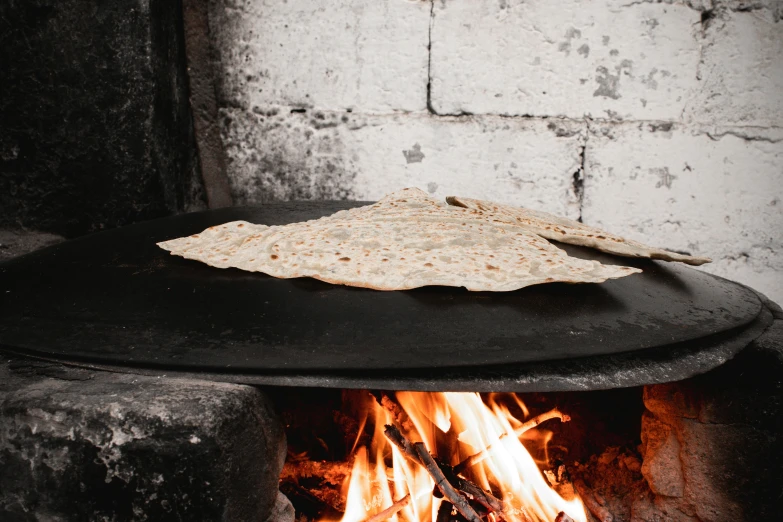 a fire with a pita on top of it next to a brick wall