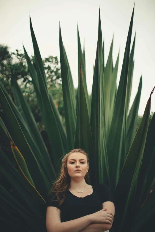 a woman is posing next to a large plant