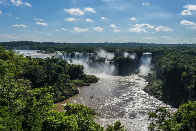 igua falls on the side of a river with a boat going under it