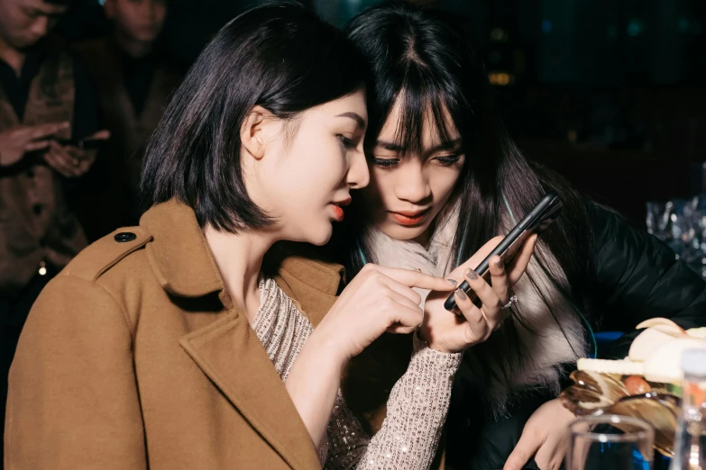 two girls are looking at soing on a cell phone