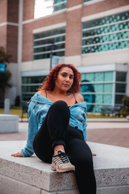 a woman with red hair sitting on concrete