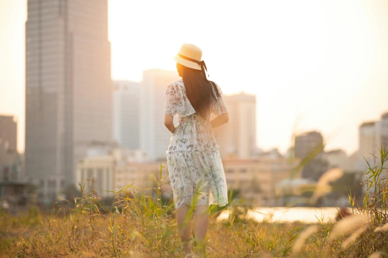 a beautiful woman in a dress and hat walking on the grass