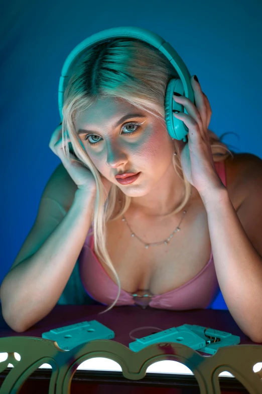 a young woman with blond hair and headphones sits at a table