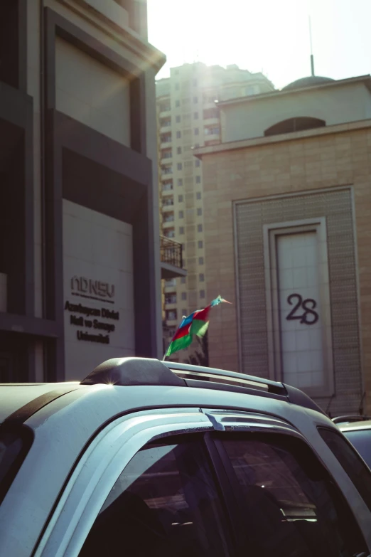 a white car with a rainbow colored bird on the roof